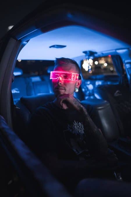 A young man with LED sunglasses sits in a car, creating a sci-fi vibe.