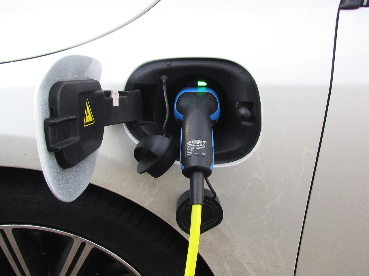 Une prise de recharge reliée à un câble jaune, branchée dans le port d’une voiture électrique blanche
